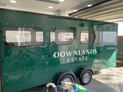 Green Downlands Estate horsebox trailer with white cut-vinyl lettering and leaf logo