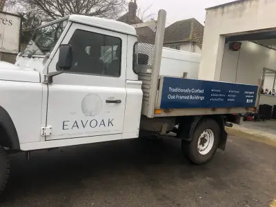 White Land Rover Defender tipper with Eavoak door logo and blue oak-buildings dropside signage