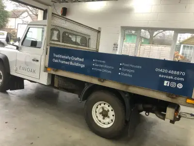 White Land Rover Defender tipper with blue Eavoak oak-framed-buildings signwriting on the bed