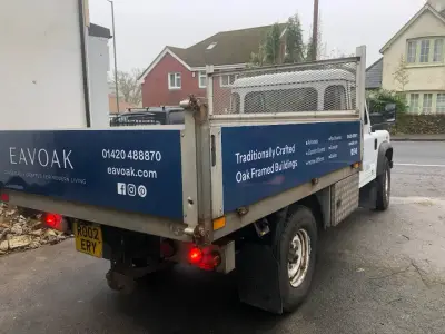 White Land Rover Defender tipper, rear angle, with blue Eavoak signwriting and tailgate logo