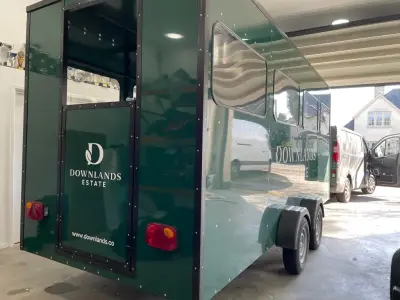 Glossy dark green Downlands Estate trailer with white leaf logo and rear door graphics