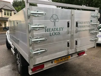 Rear of a silver dropside tipper with green Headley Logs signwriting and contact details
