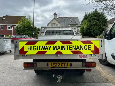 Rear tailboard of a dropside truck with red and yellow chevrons and Highway Maintenance text