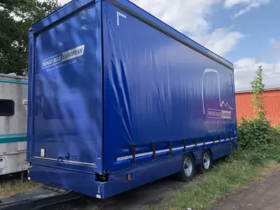 Blue curtain-side trailer with white Indigo Blue European logistics logo and website