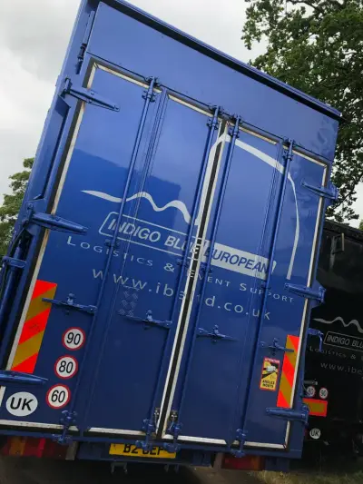 Rear doors of a blue Indigo Blue European trailer with logo, speed limits and UK stickers