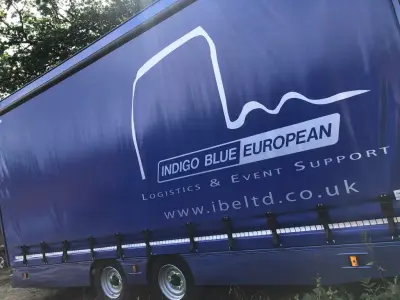 Blue Indigo Blue European curtain-side trailer with white logistics logo and web address