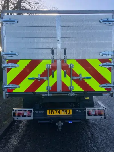 Rear of white Iveco Daily tipper truck with red and yellow chevron hazard markings