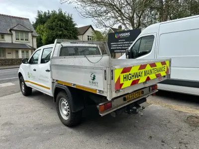 White pickup tipper with Highway Maintenance chevron tailgate and Surrey County Council graphics