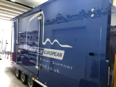 Blue Indigo Blue European covered car transporter trailer with white logo graphics