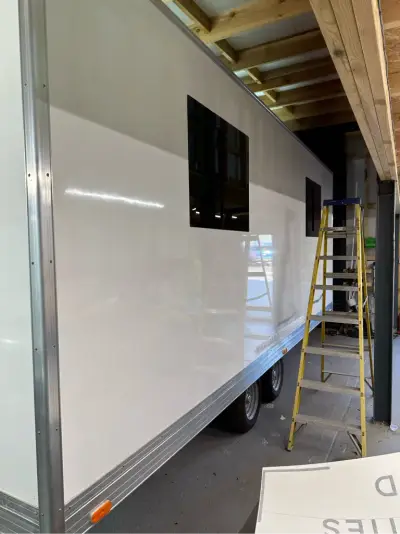 Plain white box trailer with tinted windows being fitted out in a workshop
