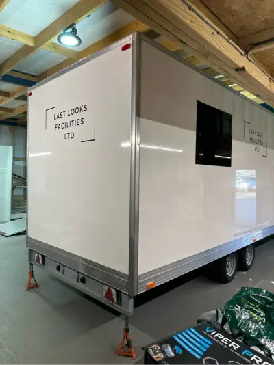 White exhibition trailer with black Last Looks Facilities Ltd signwriting and windows