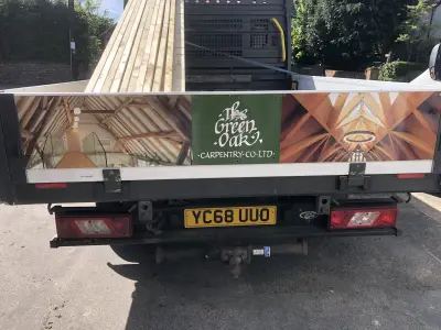 Rear of white Ford flatbed truck with The Green Oak Carpentry timber-roof graphics