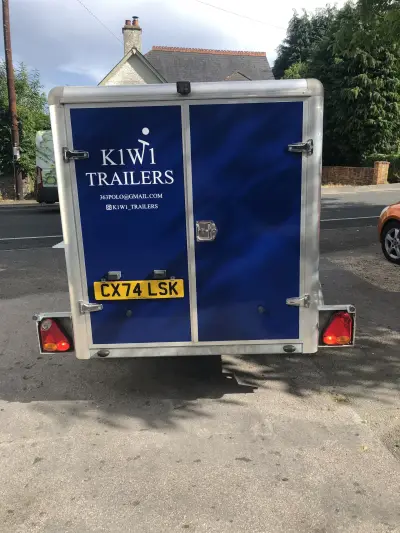 Navy blue K1W1 Trailers enclosed trailer with serving hatch, side graphics, inside a workshop