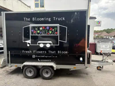 Black box trailer wrapped for The Blooming Truck, colourful flower graphics and Fresh Flowers That Bloom text