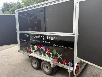 Black Blooming Truck trailer with serving hatch and colourful flower graphics along the lower panel