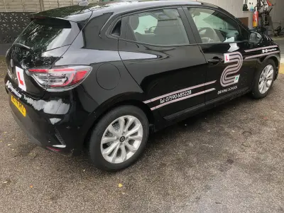 Black Renault Clio driving school car with L2P Driving School graphics, rear three-quarter view, reg ML74 AKZ