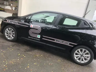 Black Renault Clio side profile with L2P Driving School graphics, parked outside a unit