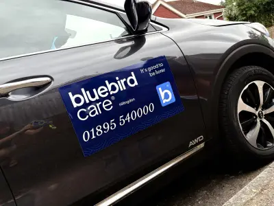 Blue Bluebird Care Hillingdon magnetic door sign on a dark Kia SUV, phone 01895 540000