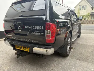 Black Nissan Navara pickup with L. Marchant Brickwork Ltd signwriting, rear corner view, reg MT66 RXS
