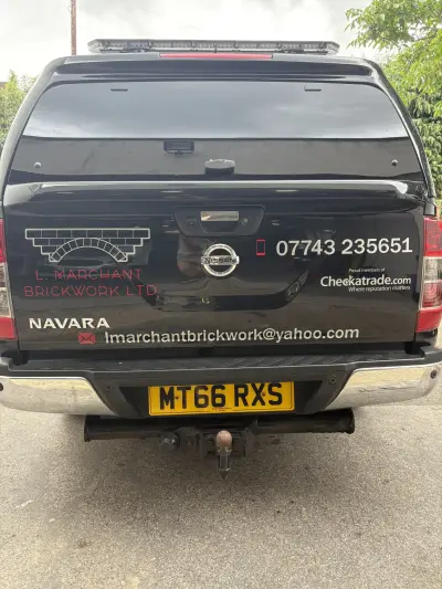 Black Nissan Navara pickup rear with L. Marchant Brickwork Ltd graphics and Checkatrade logo, reg MT66 RXS