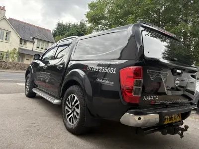 Black Nissan Navara pickup with L. Marchant Brickwork Ltd signwriting, rear three-quarter view, reg MT66 RXS