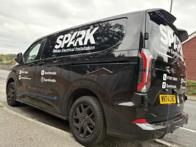 Black Ford Transit Custom van, SPARK Private Electrical Installation graphics, rear three-quarter view