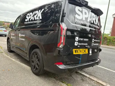 Black Ford Transit Custom van with SPARK Private Electrical Installation graphics, rear view