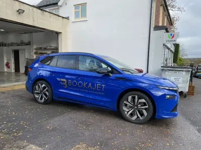 Blue Skoda Enyaq with BOOKAJET full wrap parked outside the VSIGNS shopfront