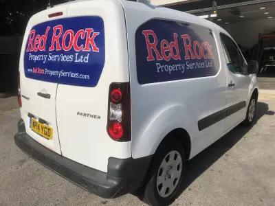 White Peugeot Partner van with blue and red Red Rock Property Services Ltd window graphics