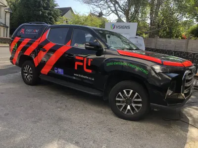 Black and red First Line firefighting pickup wrap parked near the VSIGNS sign