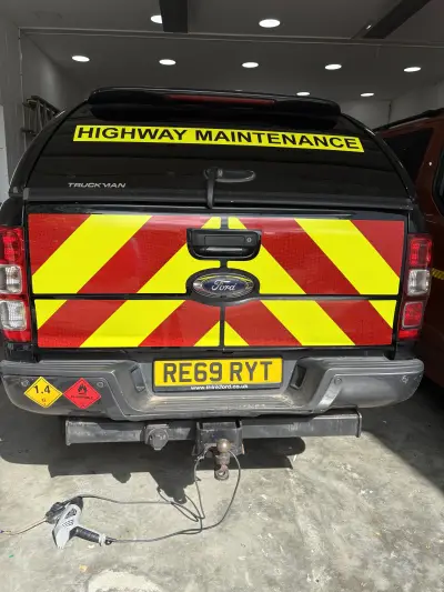 Black Ford Ranger pickup with Highway Maintenance chevron graphics, rear three-quarter view