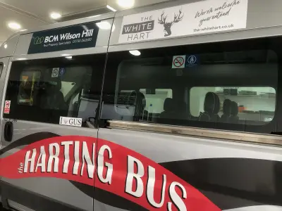 Silver minibus side wrapped as 'the Harting Bus' with White Hart and BCM Wilson Hill sponsor panels