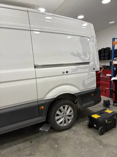 White VW Crafter van side with faint grey Lanzante elephant graphic, in a workshop