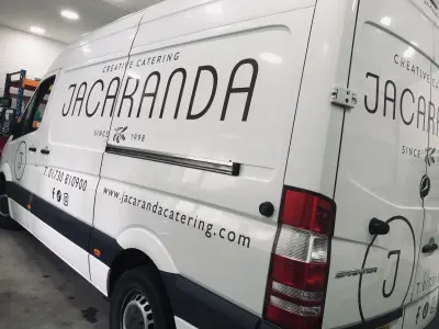 White Mercedes Sprinter van side with large Jacaranda Creative Catering wordmark graphics