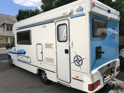 White coachbuilt motorhome with blue nautical compass and sailing-ship vinyl graphics along its side