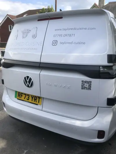 Rear of white Volkswagen ID. Buzz with Taylored Cuisine catering graphics and QR code
