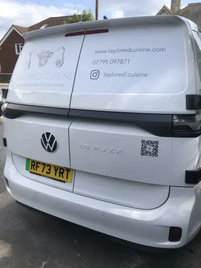 Rear of white Volkswagen ID. Buzz with Taylored Cuisine catering graphics and QR code