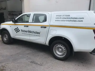 White Isuzu D-Max pickup with canopy, Robert Nicholas civil engineering graphics and yellow stripe