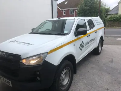 White Isuzu D-Max double-cab pickup with Robert Nicholas signwriting and reflective yellow chevron stripe