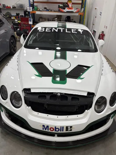Front of white Bentley race car with green stripe livery, BENTLEY windscreen and Mobil 1 graphics