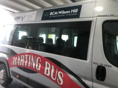 Silver minibus with red 'The Harting Bus' livery and BCM Wilson Hill sponsor graphics