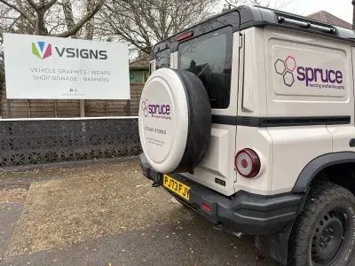 Beige Ineos Grenadier 4x4 with Spruce fencing graphics beside a VSigns forecourt sign