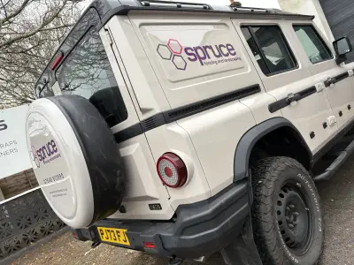 Beige Ineos Grenadier 4x4 with purple Spruce fencing and landscaping vehicle graphics