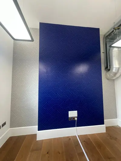 Office feature wall with blue swirl-patterned wallpaper and matching grey side walls
