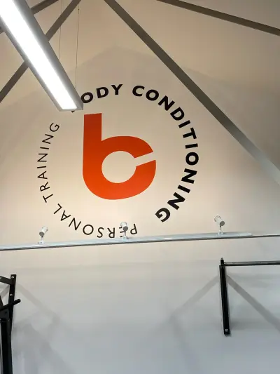 Gym wall with orange Body Conditioning Personal Training circular logo graphic