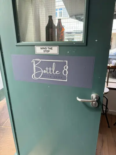 Green shop door with Bottle 8 Bottle Shop vinyl sign and Mind The Step sticker