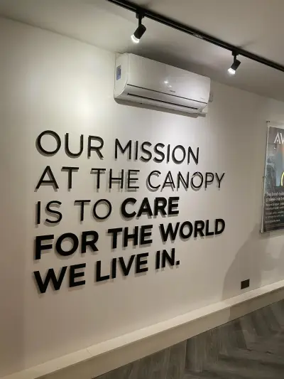 Salon wall with raised black lettering: Our mission at The Canopy is to care for the world we live in