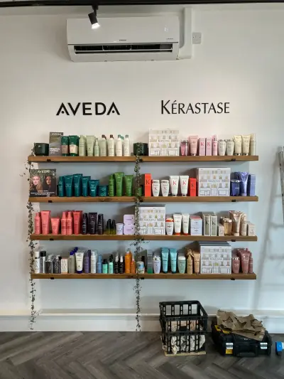 Salon retail wall with cut-vinyl Aveda and Kerastase logos above product shelving