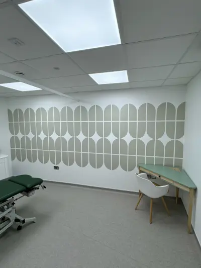 Physio room with sage-green geometric wall vinyl, treatment couch and desk