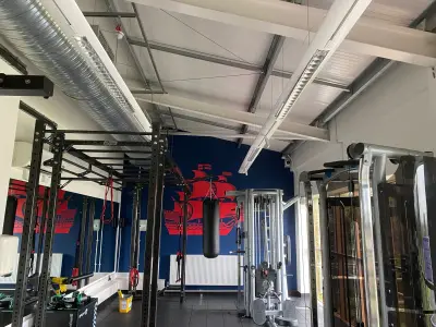 Gym interior with large red sailing-ship graphic on navy wall behind a punchbag